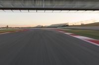 a blurry photo of a speed racing track with an overpass and bridge in the background