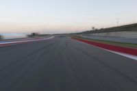 a blurry view of a race track with red and white stripes on the ground