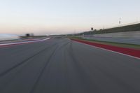 a blurry view of a race track with red and white stripes on the ground