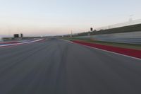 a blurry view of a race track with red and white stripes on the ground