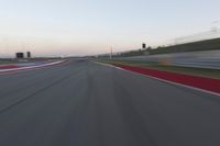 a blurry view of a race track with red and white stripes on the ground