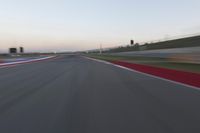 a blurry view of a race track with red and white stripes on the ground