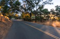 a blurred shot of some trees and a road in the background with a blurry image of an orange motorcycle