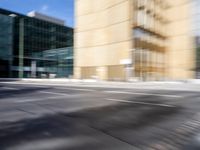 blurry view of a urban street with buildings in the background by a puddle of water