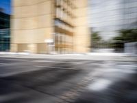 blurry view of a urban street with buildings in the background by a puddle of water