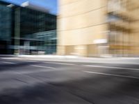 blurry view of a urban street with buildings in the background by a puddle of water