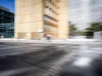blurry view of a urban street with buildings in the background by a puddle of water