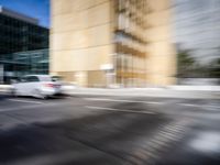 blurry view of a urban street with buildings in the background by a puddle of water