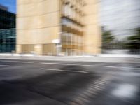 blurry view of a urban street with buildings in the background by a puddle of water