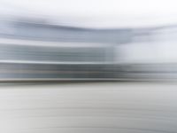 a blurry view of a modern city building in motion on a sunny day with only a red fire hydrant in front