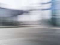 a blurry view of a modern city building in motion on a sunny day with only a red fire hydrant in front