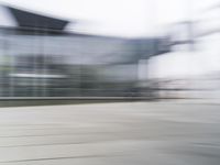 a blurry view of a modern city building in motion on a sunny day with only a red fire hydrant in front