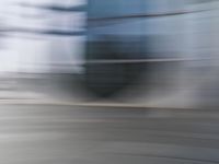 a blurry view of a modern city building in motion on a sunny day with only a red fire hydrant in front