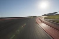 a blurry photo from the front of a car driving on an empty track with red and white stripeing