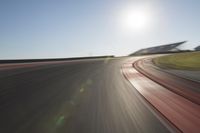 a blurry photo from the front of a car driving on an empty track with red and white stripeing