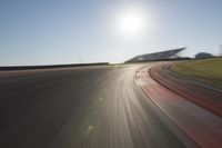 a blurry photo from the front of a car driving on an empty track with red and white stripeing