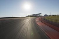 a blurry photo from the front of a car driving on an empty track with red and white stripeing