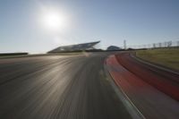 a blurry photo from the front of a car driving on an empty track with red and white stripeing