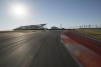 a blurry photo from the front of a car driving on an empty track with red and white stripeing