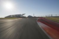 a blurry photo from the front of a car driving on an empty track with red and white stripeing