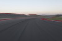 a blurry photo of a curve with one car going down it at dusk,