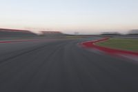 a blurry photo of a curve with one car going down it at dusk,