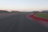 a blurry photo of a curve with one car going down it at dusk,
