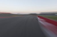 a blurry photo of a curve with one car going down it at dusk,