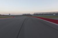 a blurry photo of a curve with one car going down it at dusk,