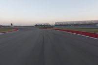 a blurry photo of a curve with one car going down it at dusk,