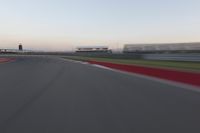 a blurry photo of a curve with one car going down it at dusk,