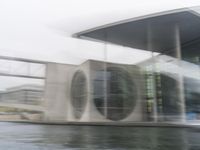 blurry photo of a car parked near an art museum by a river and building