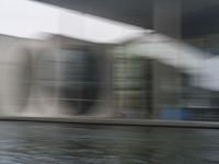 blurry photo of a car parked near an art museum by a river and building