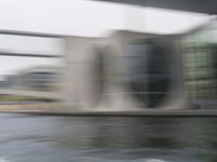 blurry photo of a car parked near an art museum by a river and building