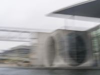 blurry photo of a car parked near an art museum by a river and building