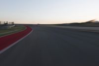 a blurry picture of a speed car on a race track with red tires running along the side of the track