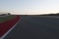 a blurry picture of a speed car on a race track with red tires running along the side of the track