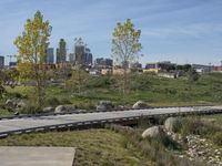 an empty parking lot is next to the boardwalk with rocks, shrubs and bushes in front of a city skyline