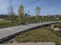 an empty parking lot is next to the boardwalk with rocks, shrubs and bushes in front of a city skyline