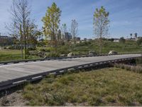 an empty parking lot is next to the boardwalk with rocks, shrubs and bushes in front of a city skyline