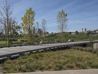 an empty parking lot is next to the boardwalk with rocks, shrubs and bushes in front of a city skyline