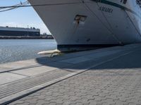 a large white boat at dock with people walking by it's side line and another boat nearby