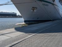 a large white boat at dock with people walking by it's side line and another boat nearby