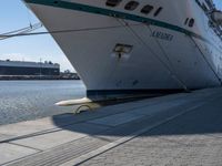 a large white boat at dock with people walking by it's side line and another boat nearby