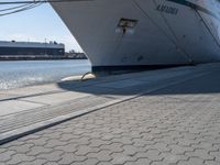 a large white boat at dock with people walking by it's side line and another boat nearby