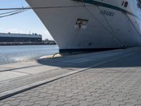 a large white boat at dock with people walking by it's side line and another boat nearby