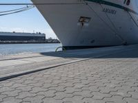 a large white boat at dock with people walking by it's side line and another boat nearby