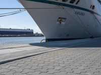 a large white boat at dock with people walking by it's side line and another boat nearby