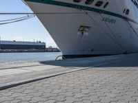 a large white boat at dock with people walking by it's side line and another boat nearby