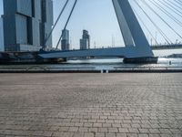 a yellow and white boat in the water next to buildings on a bridge with a few people around it